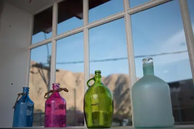 four glass bottles sitting on a window sill at El Encanto in Lunahuaná