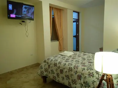 a bedroom with a bed and a tv on the wall at Hotel Elizabeth Hoss in Sayán