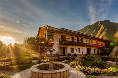 a house with a fountain in front of a mountain at Sonesta Posadas del Inca - Valle Sagrado Yucay Urubamba in Urubamba