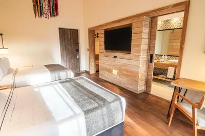 a bedroom with two beds and a television and a table at Sonesta Posadas del Inca - Valle Sagrado Yucay Urubamba in Urubamba