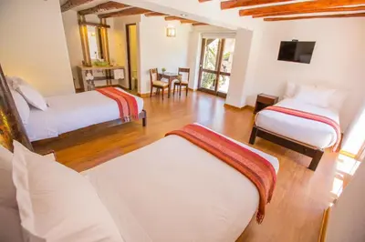 a bedroom with two beds and a living room with a table at Tierra Viva Valle Sagrado Hotel in Urubamba