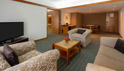 a living room with two couches and a television at Sonesta Hotel El Olivar in Lima