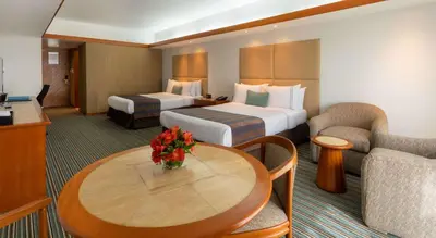 a hotel room with two beds and a table at Sonesta Hotel El Olivar in Lima