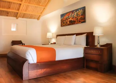 a bedroom with a large bed and a painting on the wall at Waman Qorikancha in Cusco