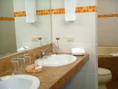 a bathroom with two sinks and a toilet and a mirror at Kajaca Suite Hotel in Huacho