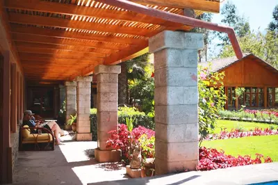 two people sitting under a wooden pergola in a garden at Hotel San Agustin Urubamba in Urubamba