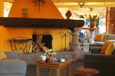 a living room with a fireplace with couches and a table at Hotel San Agustin Urubamba in Urubamba