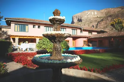 a fountain in the middle of a yard with a house at Hotel San Agustin Urubamba in Urubamba