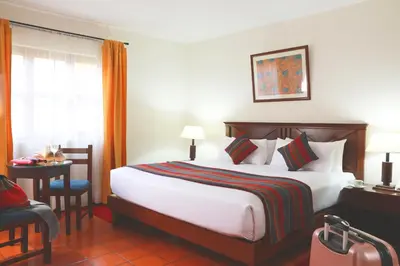 a hotel room with a large bed and a chair at Hotel San Agustin Urubamba in Urubamba