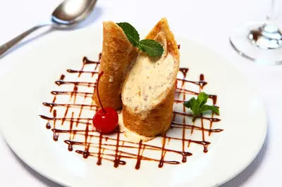 a white plate with a sandwich with chocolate sauce and a cherry at San Agustin Monasterio de la Recoleta in Urubamba