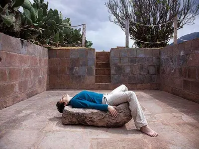 a man laying on top of a rock at San Agustin Monasterio de la Recoleta in Urubamba