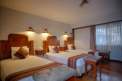 a hotel room with three beds and a window at Munay Wasi Inn in Cusco