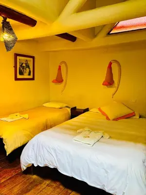 two beds in a room with red bells on the wall at La Casa de Campo in Cusco