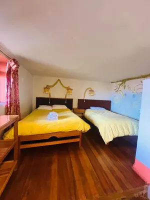 two beds in a room with wooden floors at La Casa de Campo in Cusco
