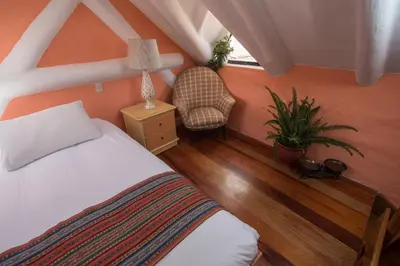 a bedroom with a bed and a chair and a window at Inkarri Cusco in Cusco