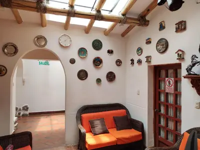 a living room with an orange chair and plates on the wall at Hosteria de Anita in Cusco