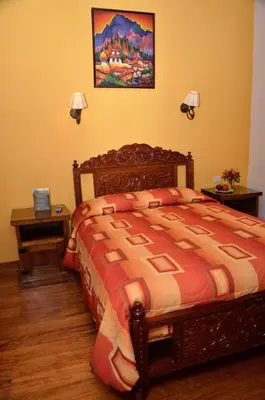 a bedroom with a bed and two night stands and two lamps at Hostal Mallqui in Cusco