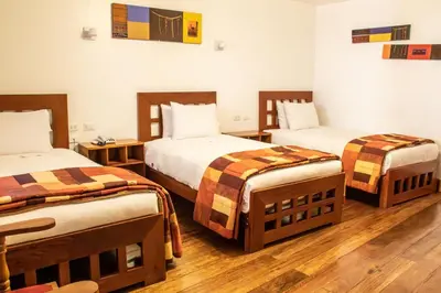 a hotel room with two beds and two tables at Amaru Colonial in Cusco