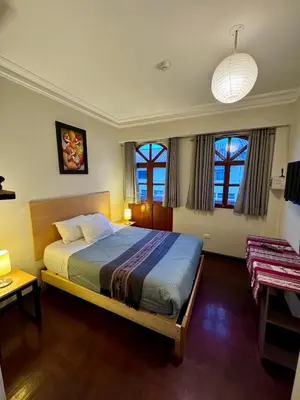 a bedroom with a bed and two windows at TATA Hotel Boutique in Cusco
