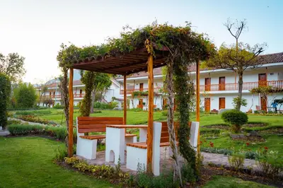 a wooden bench in a garden with a pergola at Hotel Agustos Urubamba in Urubamba