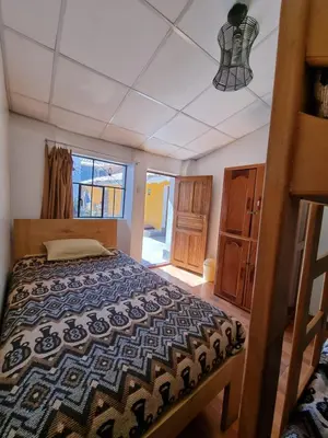 a bedroom with a bed and a large window at Chelitos Backpacker in Cusco