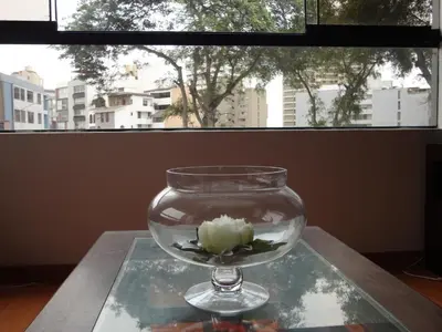 a glass vase with a flower in it on a table at Miraflores Bello Apartamento in Lima