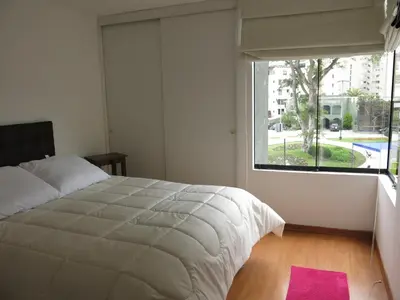 a bedroom with a large bed and a large window at Miraflores Bello Apartamento in Lima