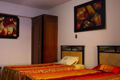 two beds in a room with a painting on the wall at Tinoco Apart Hotel in Ayacucho