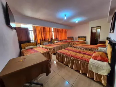a group of beds in a room with tables at Tinoco Apart Hotel in Ayacucho