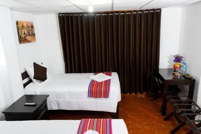 a hotel room with two beds and a desk at Peru Coca B&B Machupicchu in Machu Picchu