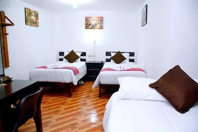 a room with two beds and a desk and a table at Peru Coca B&B Machupicchu in Machu Picchu