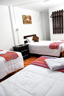 a room with two beds and a table with a lamp at Peru Coca B&B Machupicchu in Machu Picchu