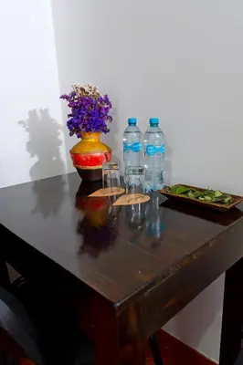 a table with bottles and glasses and a vase with flowers at Peru Coca B&B Machupicchu in Machu Picchu