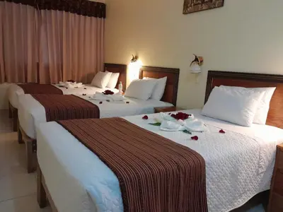 two beds in a hotel room with flowers on them at Margarita's House Machupicchu in Machu Picchu
