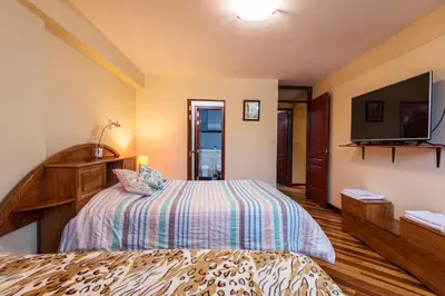 a bedroom with a bed and a flat screen tv at Espacioso confortable apartamento familia in Cusco