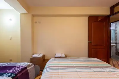 a small bedroom with two beds and a window at Espacioso confortable apartamento familia in Cusco