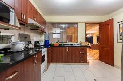 a large kitchen with wooden cabinets and appliances at Espacioso confortable apartamento familia in Cusco
