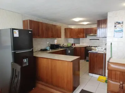 a kitchen with wooden cabinets and a black refrigerator at Apartamento PARDO CCA in Lima