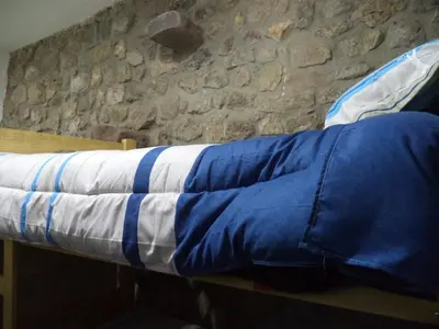 a bed with a blue and white blanket on it at Gringo's Wasi in Cusco