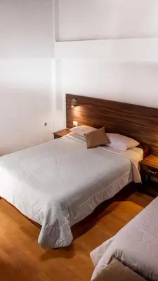 a bedroom with a large white bed with a wooden headboard at SAN BLAS PLAZA INn in Cusco
