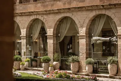 a building with arches with potted plants and flowers at Monasterio, A Belmond Hotel, Cusco in Cusco
