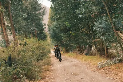 two people riding a bike down a dirt road at Rio Sagrado, A Belmond Hotel, Sacred Valley in Urubamba