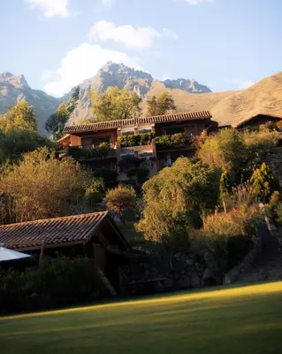 a house on a hill with mountains in the background at Rio Sagrado, A Belmond Hotel, Sacred Valley in Urubamba