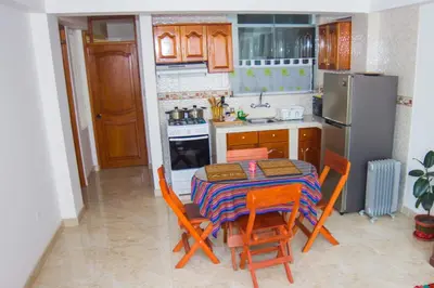 a kitchen with a table and chairs and a refrigerator at Boutique Amaru Wasi in Cusco