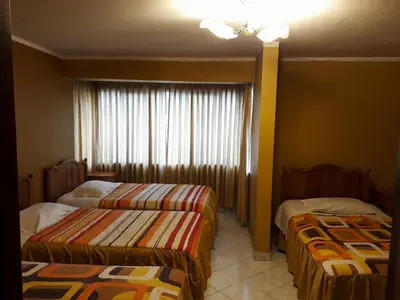 a hotel room with two beds and a window at Prince Hospedaje in Ayacucho