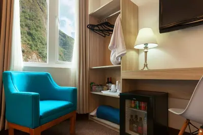 a room with a blue chair and a window at Inti Punku Machupicchu Hotel & Suites in Machu Picchu