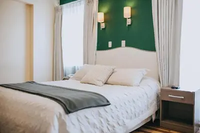 a bedroom with a white bed with a green wall at Anden Inca Hotel in Cusco