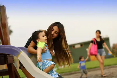 a woman holding a little girl on a slide at Casa Andina Standard Chincha in Chincha Alta