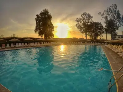 a large swimming pool with a sunset in the background at Casa Andina Standard Chincha in Chincha Alta