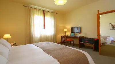 a bedroom with a bed and a desk with a computer at LP Los Portales Hotel Tarma in Tarma
